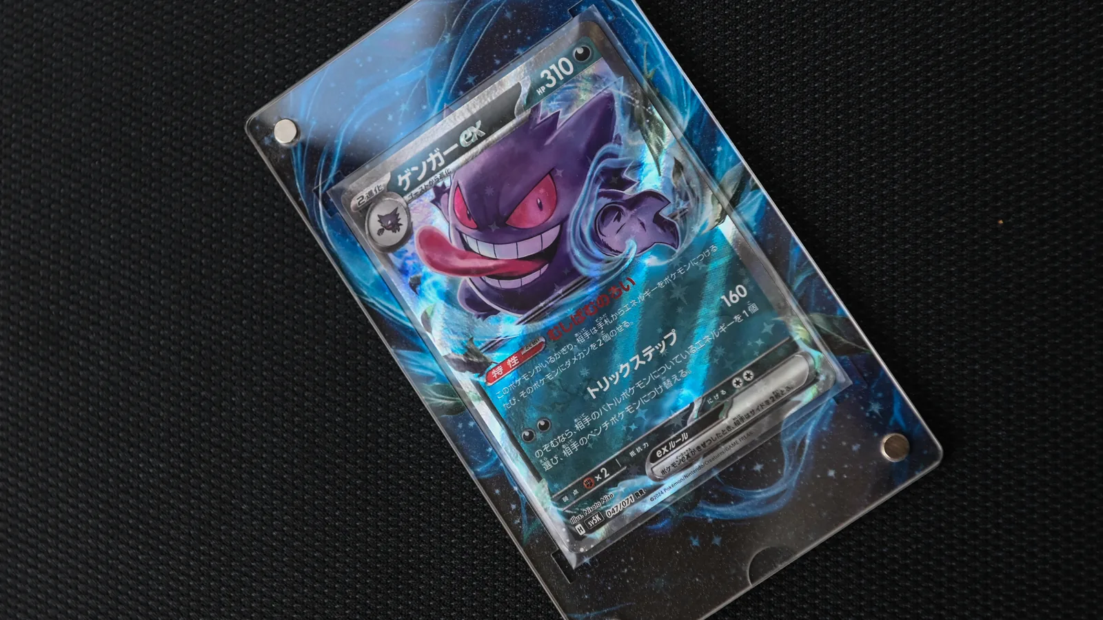 A graded Gengar ex slab held in a clear magnetic acrylic display case on a black textured surface